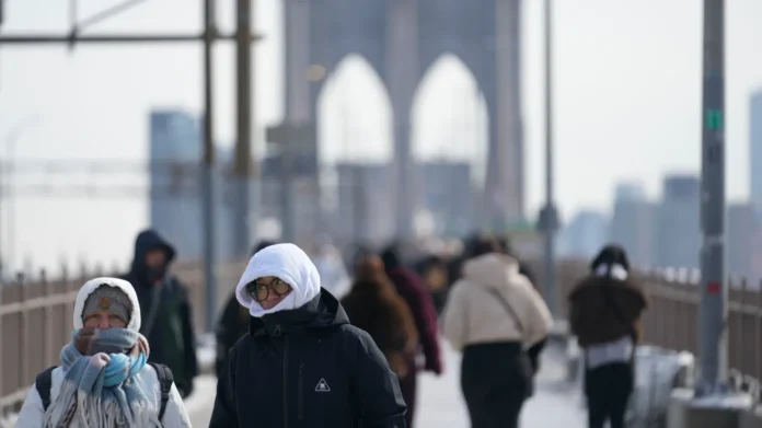Peatones abrigados cruzan el puente de Brooklyn en Nueva York. Crédito: Seth Wenig | AP