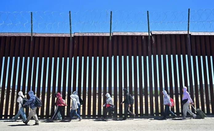 Inmigrantes caminan junto al muro fronterizo con Estados Unidos del lado de territorio de México. FREDERIC J. BROWN/ AFP